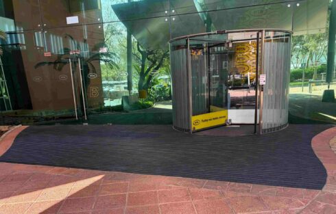 MTN building entrance featuring a large black ribbed entrance mat installed around the revolving glass door.