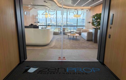 Custom Zenprop Property Holdings logo entrance mat installed outside a modern glass office reception, reinforcing the company’s branding at the entrance.